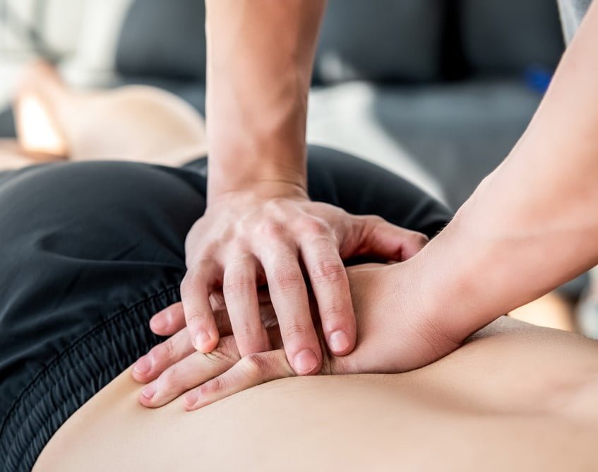 A close-up of hands performing a chiropractic adjustment on a person's lower back - Chiropractor Flower Mound TX A close-up of hands performing a chiropractic adjustment on a person's lower back - Chiropractor Flower Mound TX