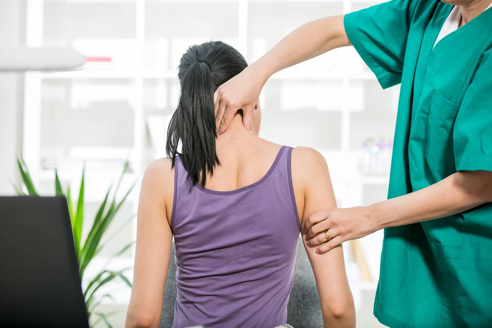 A chiropractor examining and making adjustment to a woman patient's neck pain - Chiropractor Flower Mound TX