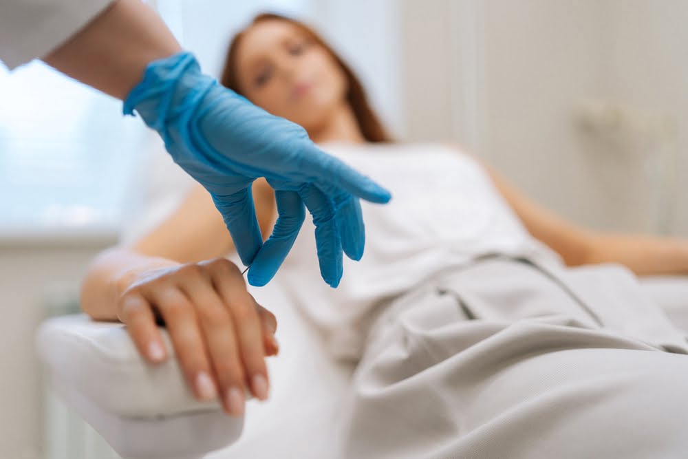 A chiropractor wearing blue gloves prepares to treat a patient who is lying down - Chiropractor Flower Mound TX A chiropractor wearing blue gloves prepares to treat a patient who is lying down - Chiropractor Flower Mound TX