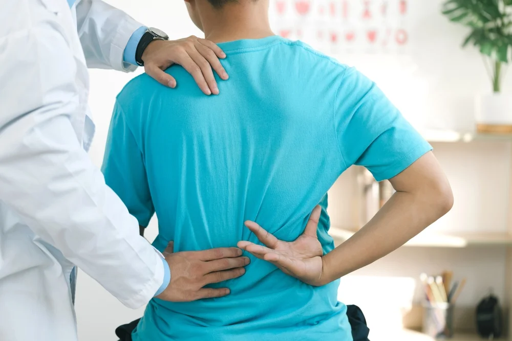 A chiropractor examines a patient’s lower back during a consultation - Chiropractor Flower Mound TX